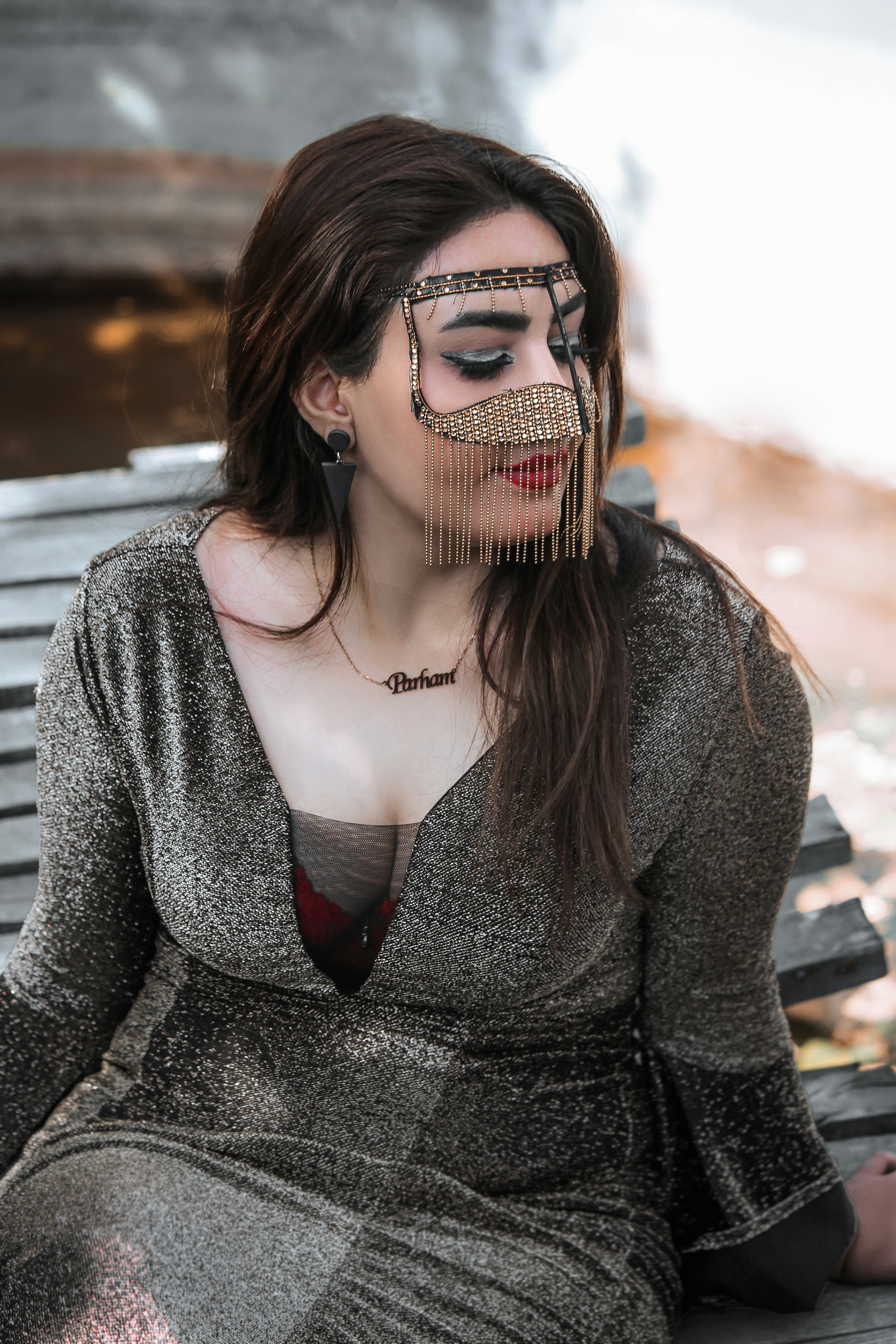 A woman sitting on top of a bench wearing a silver dress
