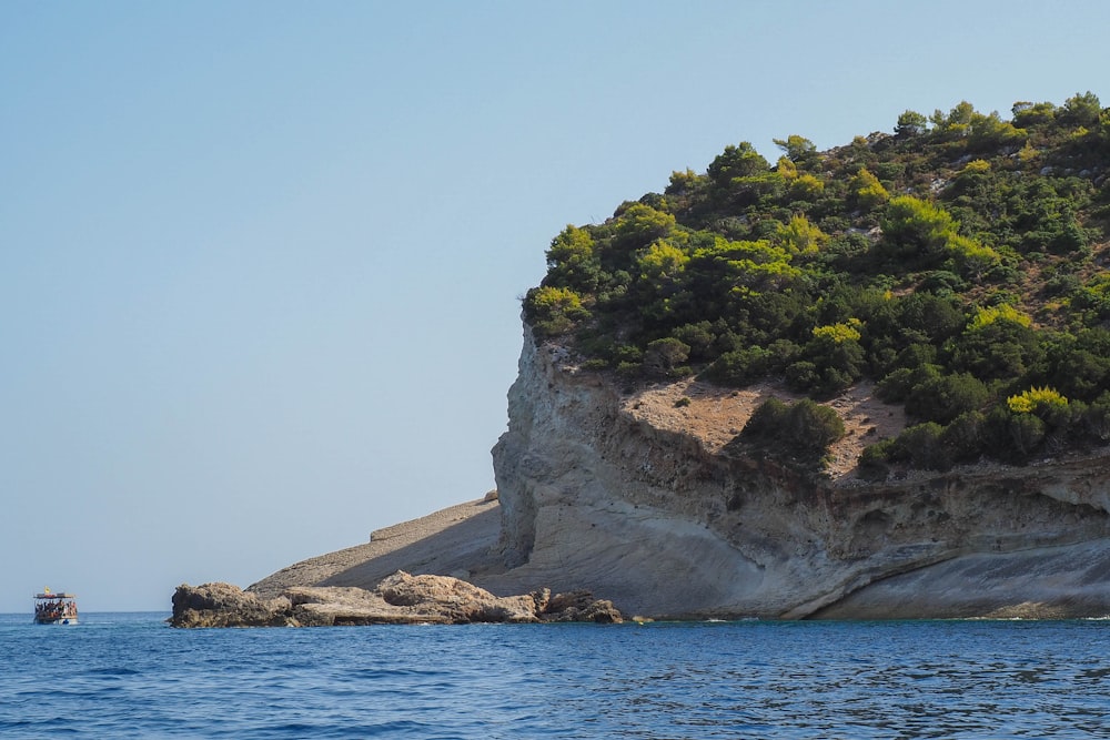 a boat is in the water near a large rock