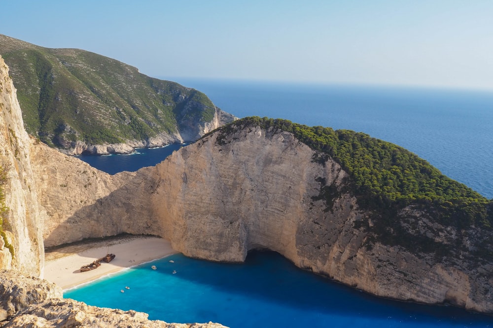 a boat sits on the beach next to a cliff