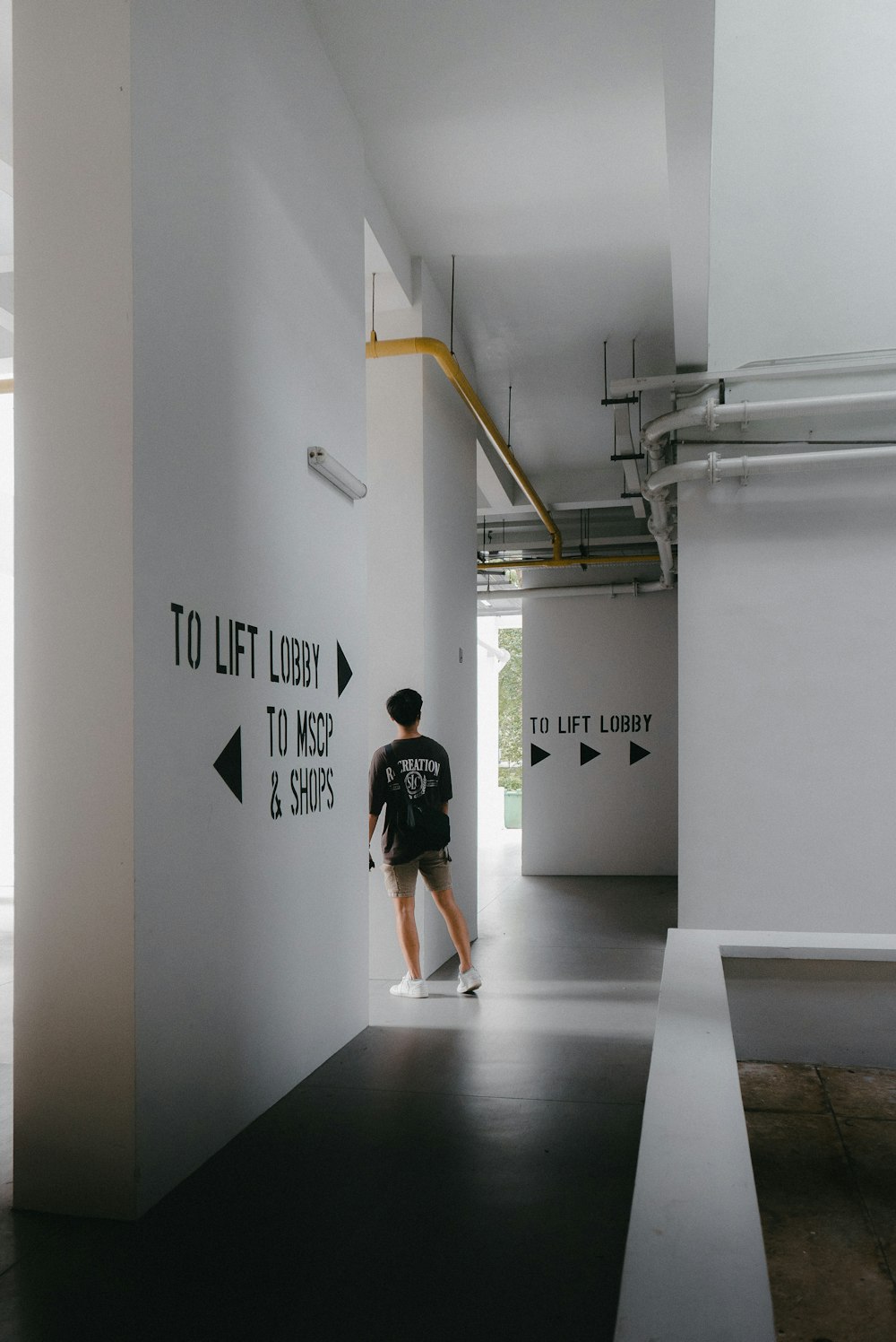 a man standing in a hallway with a sign on the wall