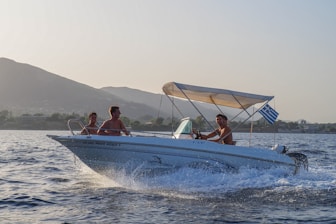 A modern motorboat cruising near a rocky Greek coastline with white buildings.