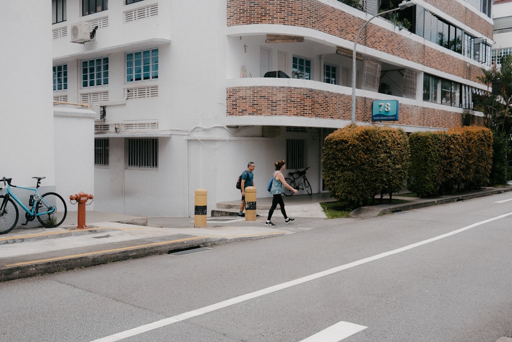 a couple of people walking down a street next to a tall building