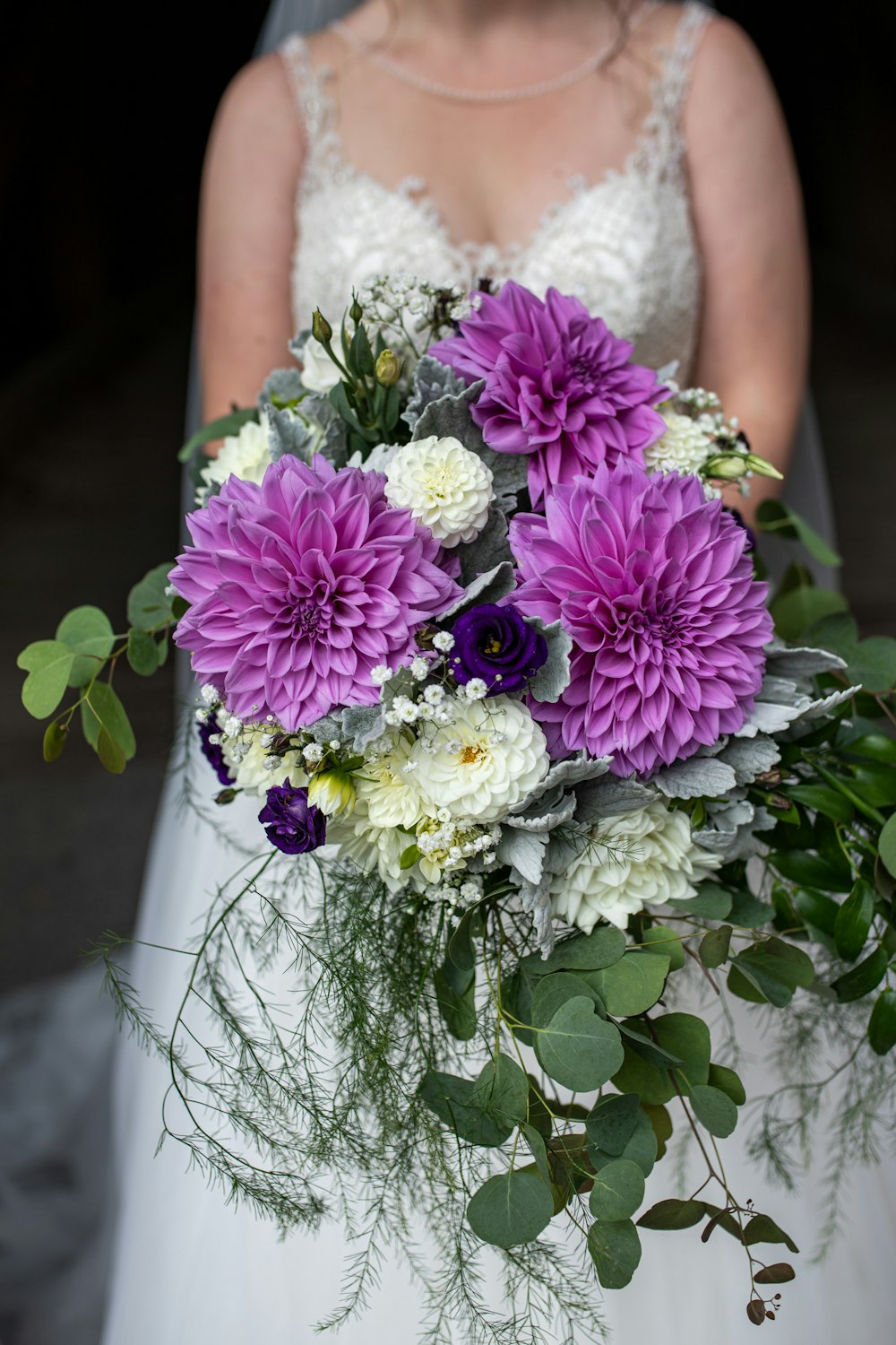 a bride holding a bouquet of purple and white flowers