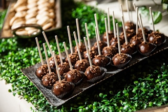 A rustic wooden tray filled with assorted gourmet cake pops.