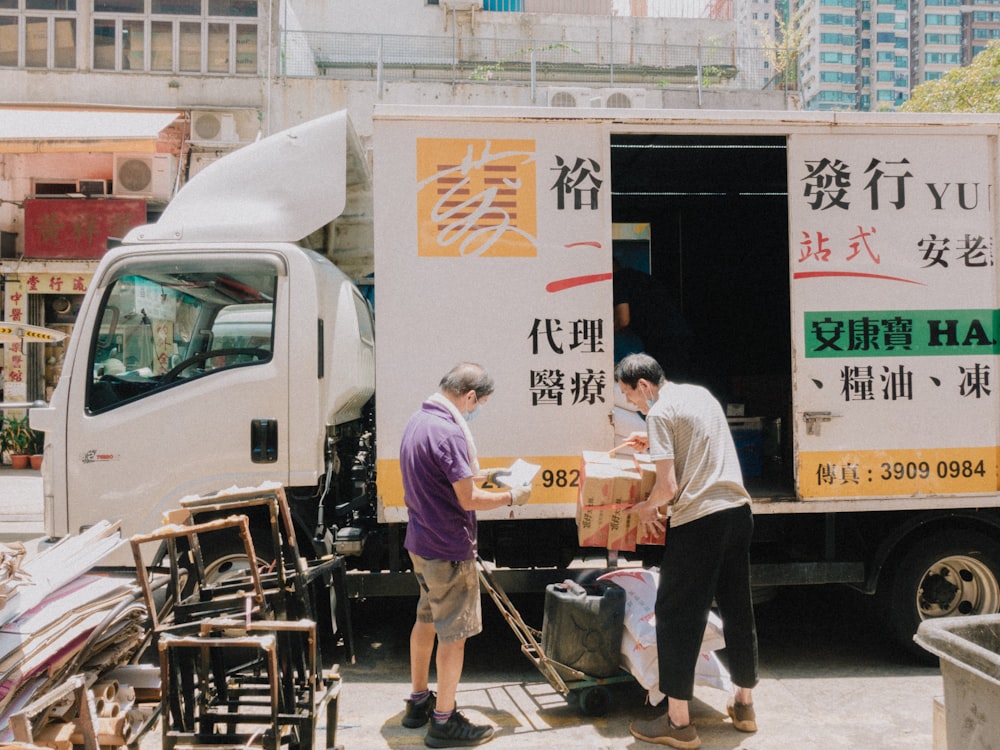 a couple of men standing next to a truck