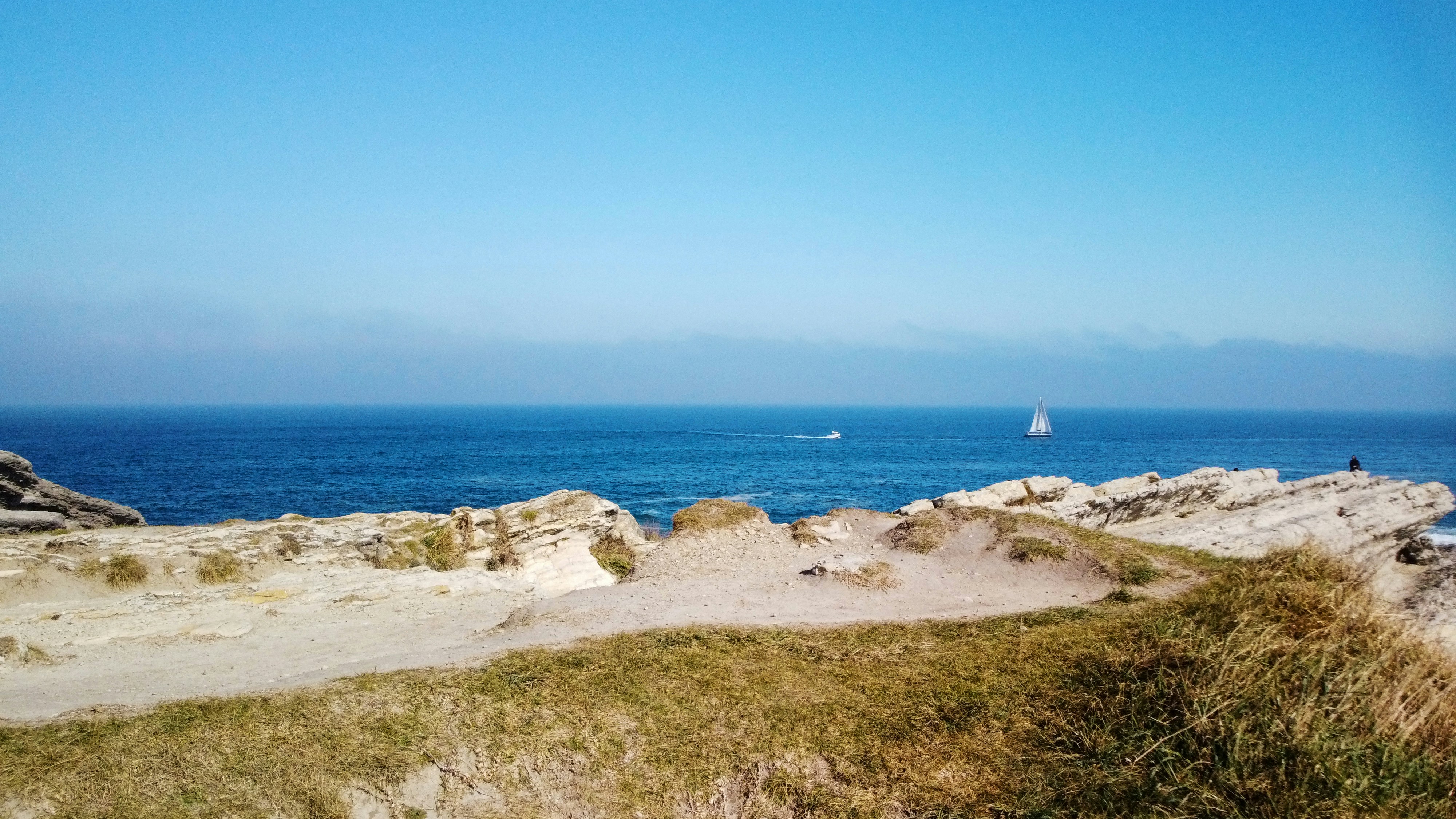 a beach with a sailboat in the distance