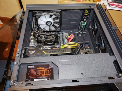 An open computer case reveals various internal components including a graphics card labeled 'Geforce GTX', a power supply unit marked 'XP800 800W', and a cooling fan. There are several visible cables and wires, some of which are neatly organized. The build appears clean and professionally assembled.