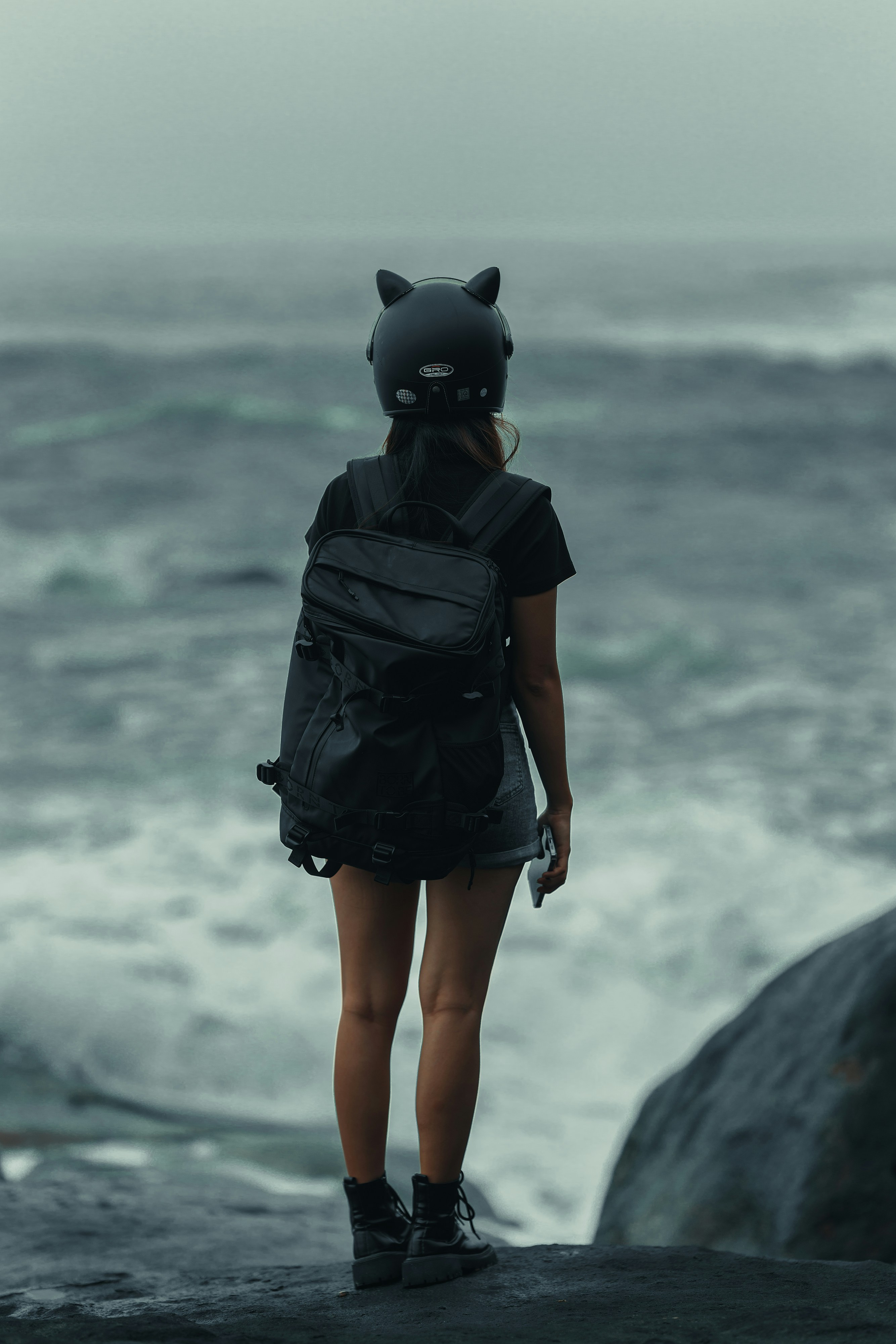 A woman standing on a rock looking out at the ocean photo – Free Girl ...