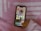 A smartphone displaying a social media folder is being held by a hand wearing a pink sweater. The background consists of a pink and white patterned fabric.