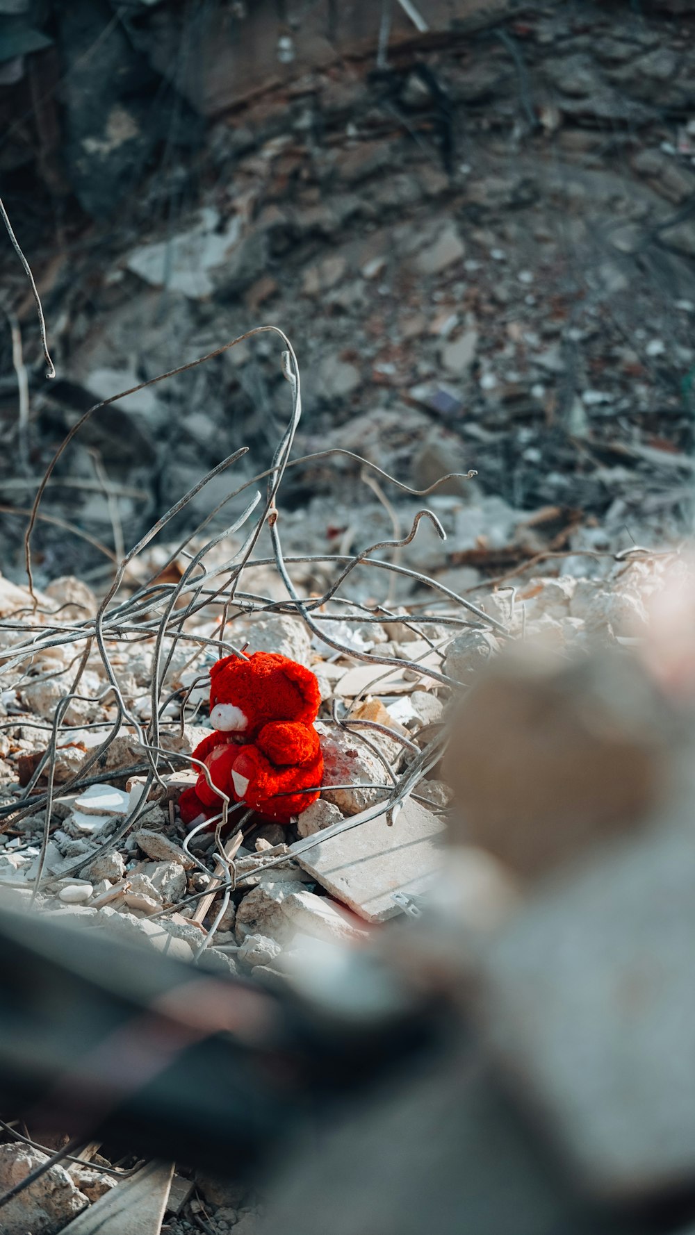 a red teddy bear sitting on top of a pile of rubble