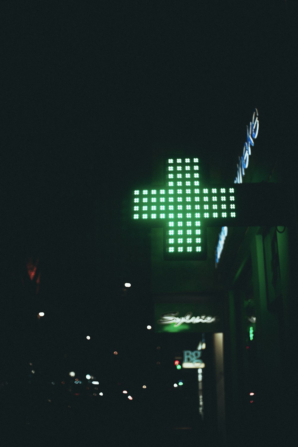 a green cross sign lit up in the dark