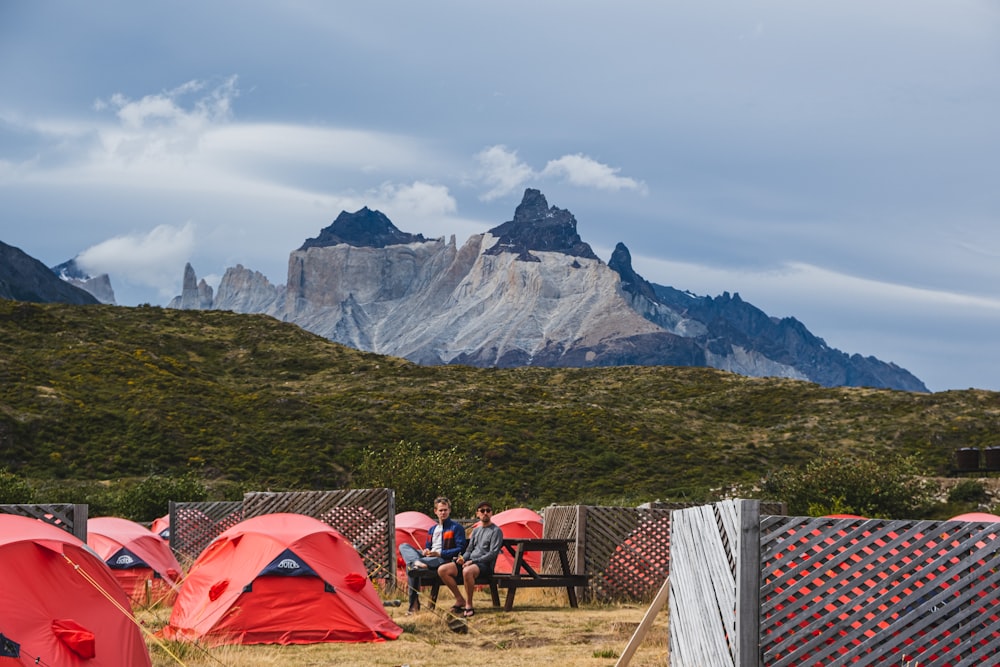 a group of people sitting on a bench next to tents