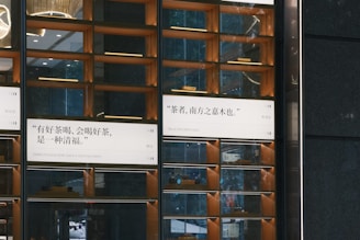 A modern, visually appealing wall display featuring quotes in both Chinese and English. The wall consists of multiple rectangular sections with mirror-like surfaces and ambient lighting. Wood accents highlight the design, creating a sophisticated and warm atmosphere. Some sections reflect elements from the surrounding environment, enhancing the overall aesthetic.