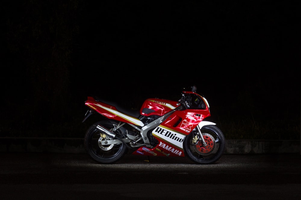 a red and white motorcycle parked in the dark