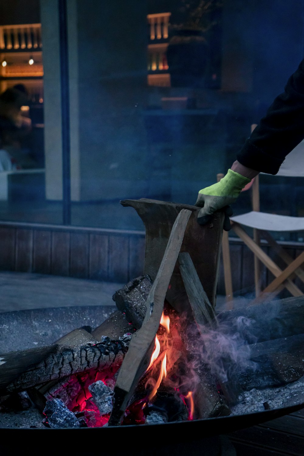 uma pessoa em luvas verdes cozinhando alimentos sobre uma fogueira aberta