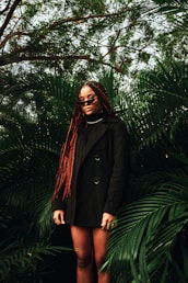 a woman with red dreadlocks standing in front of a tree