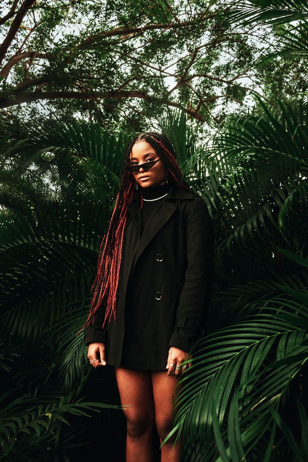 a woman with red dreadlocks standing in front of a tree