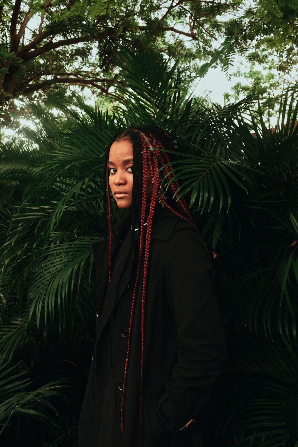 a woman with red dreadlocks standing in front of a tree