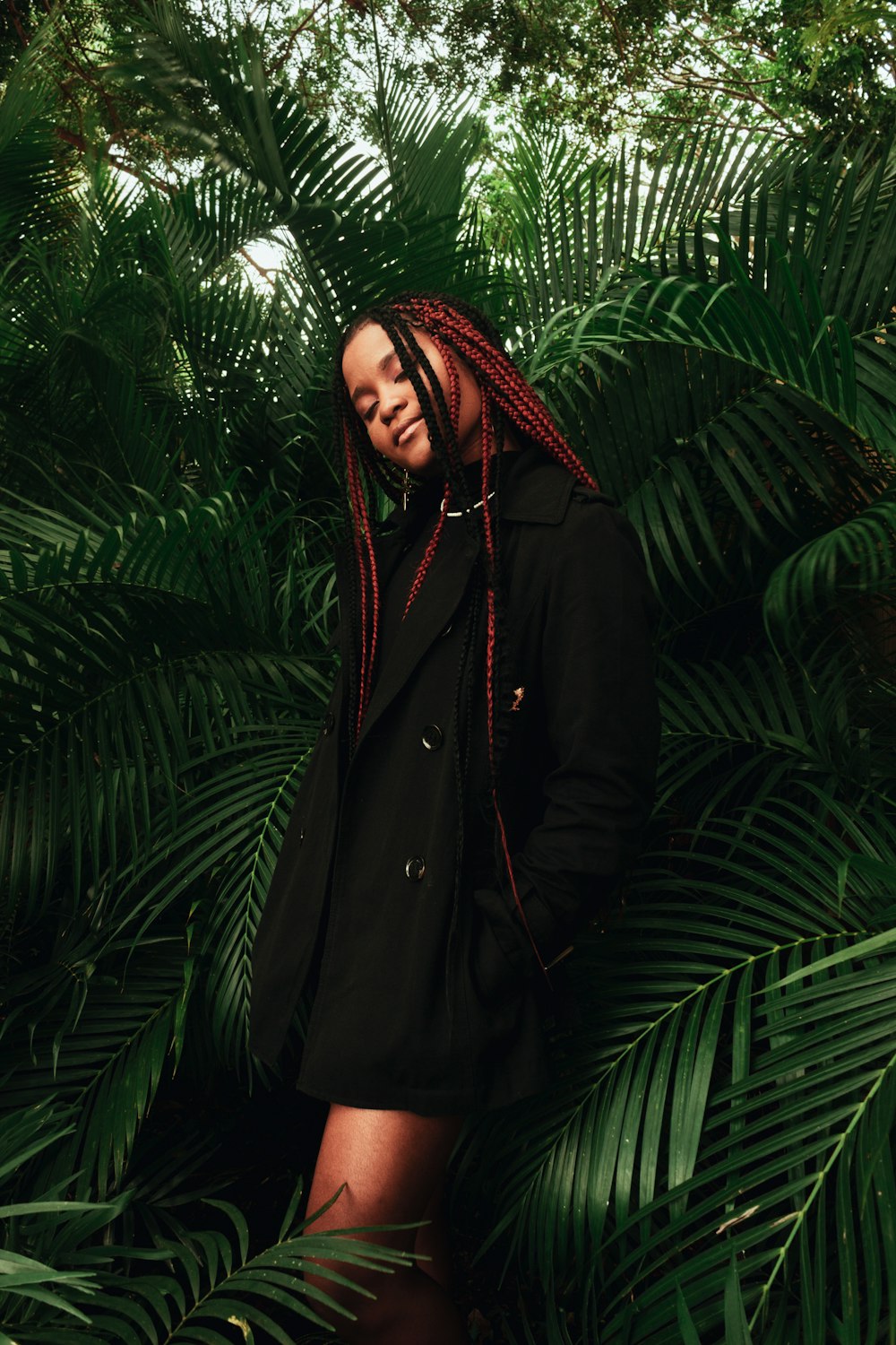 a woman with red dreadlocks standing in a jungle