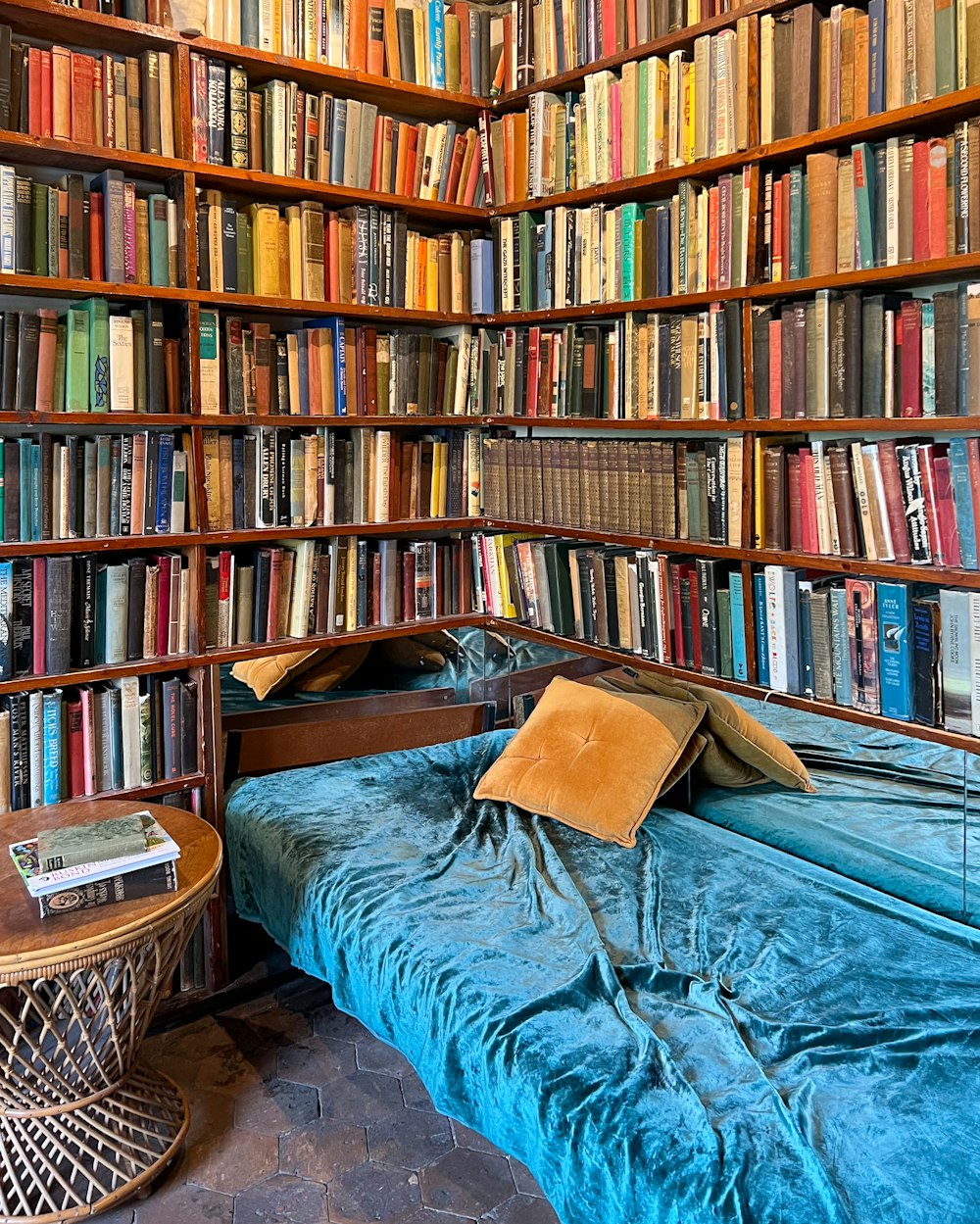 a bed in a room with a lot of books on the shelves
