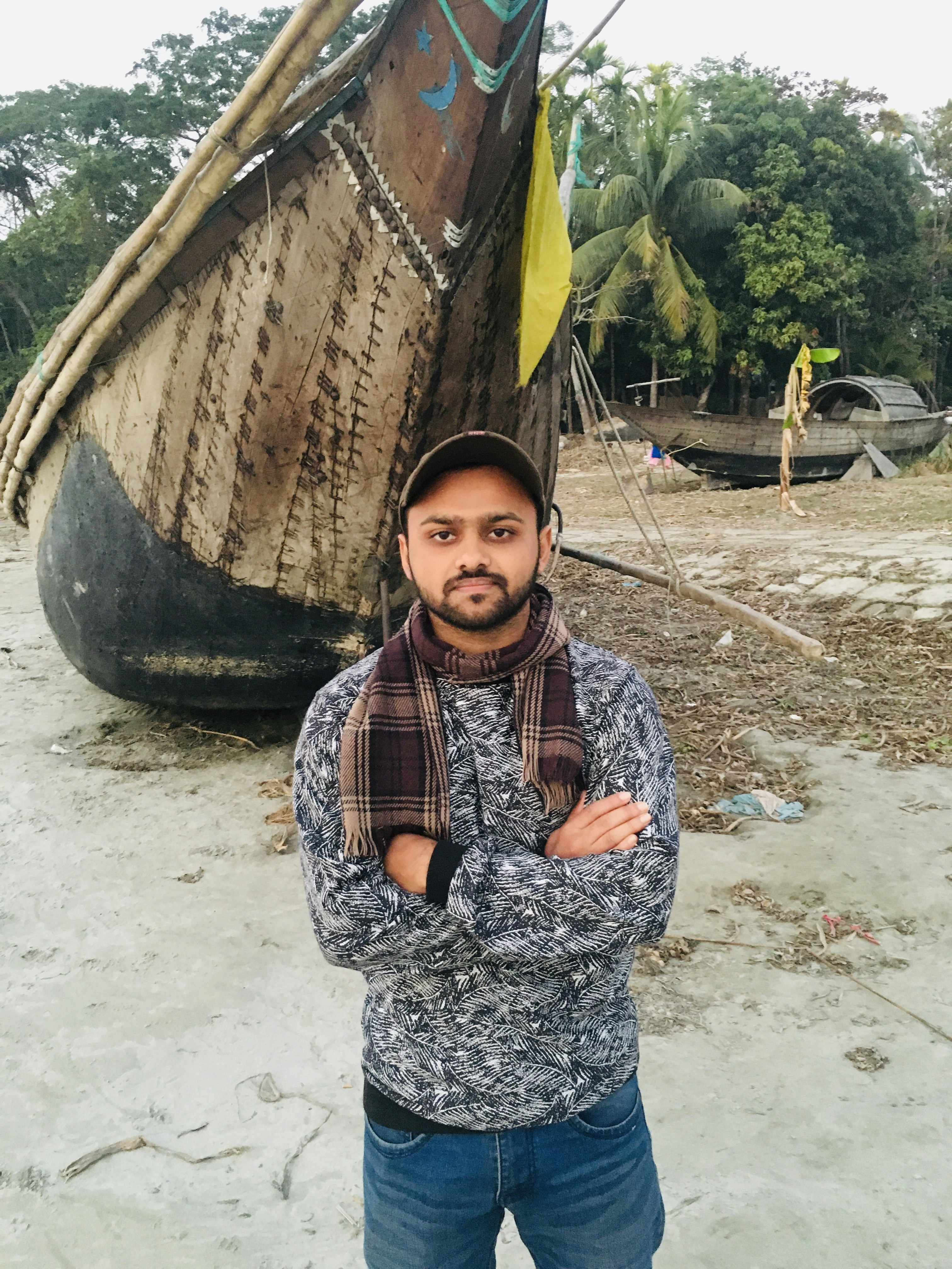 Seorang pria berdiri di depan perahu di pantai