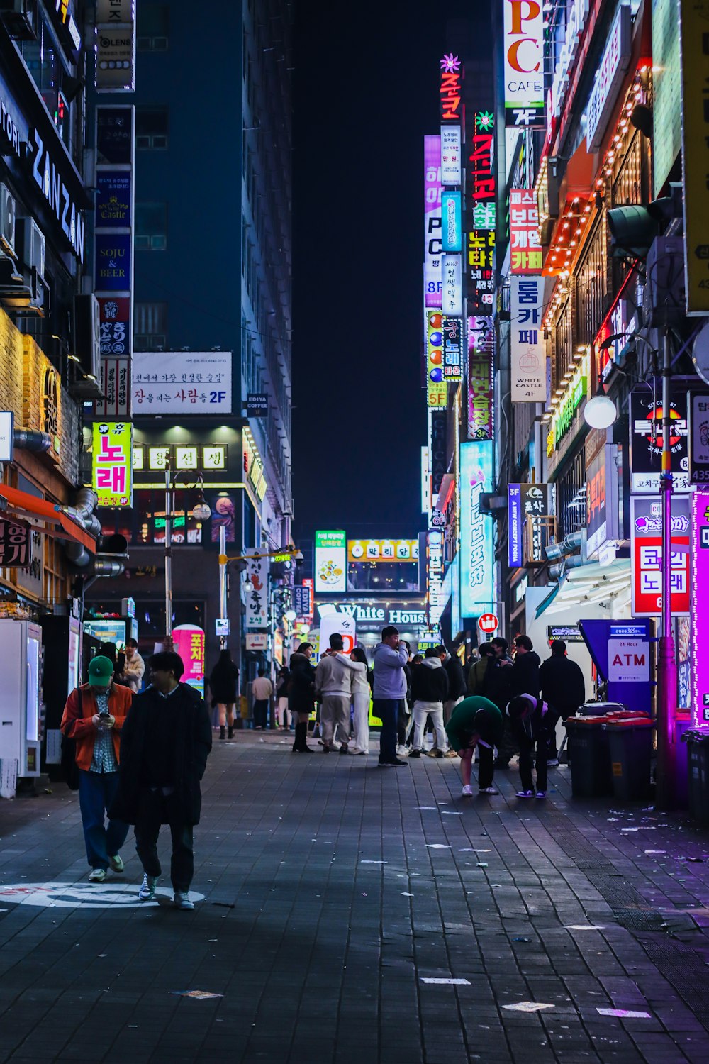 a group of people walking down a street next to tall buildings