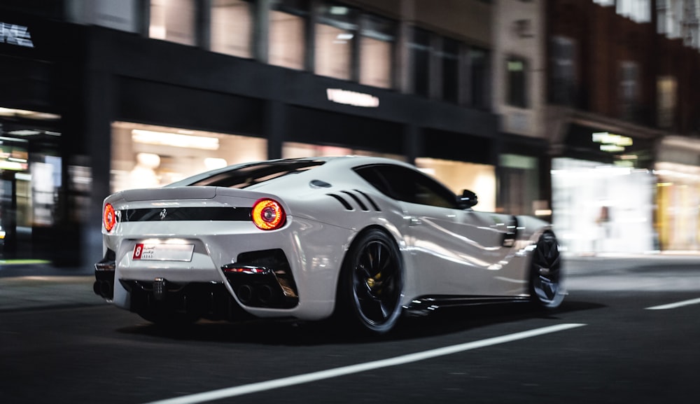 a white sports car driving down a city street