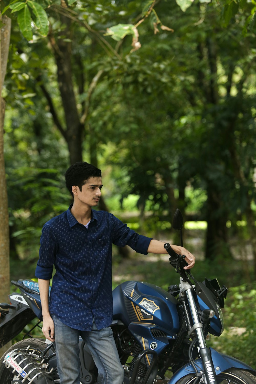 a man standing next to a blue motorcycle