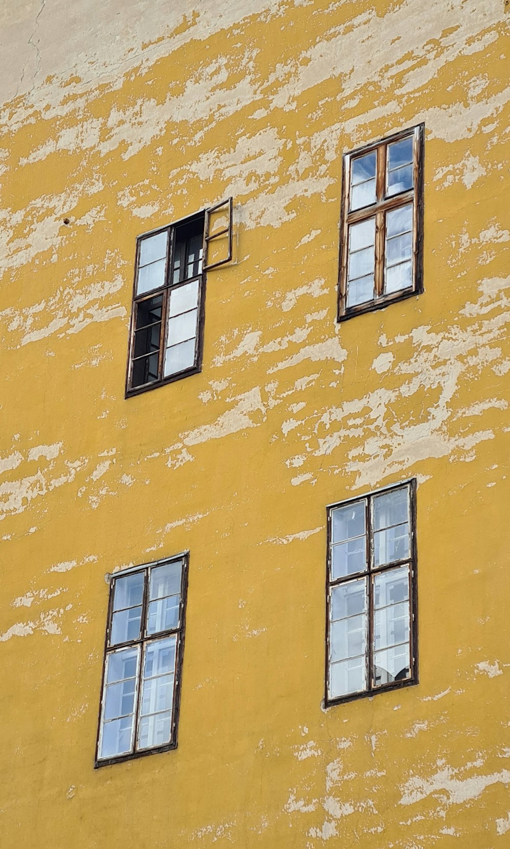 a yellow building with four windows and a clock