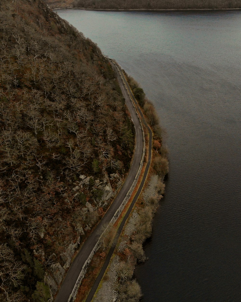 a winding road next to a body of water