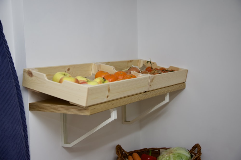 a wooden tray of fruit and vegetables on a shelf