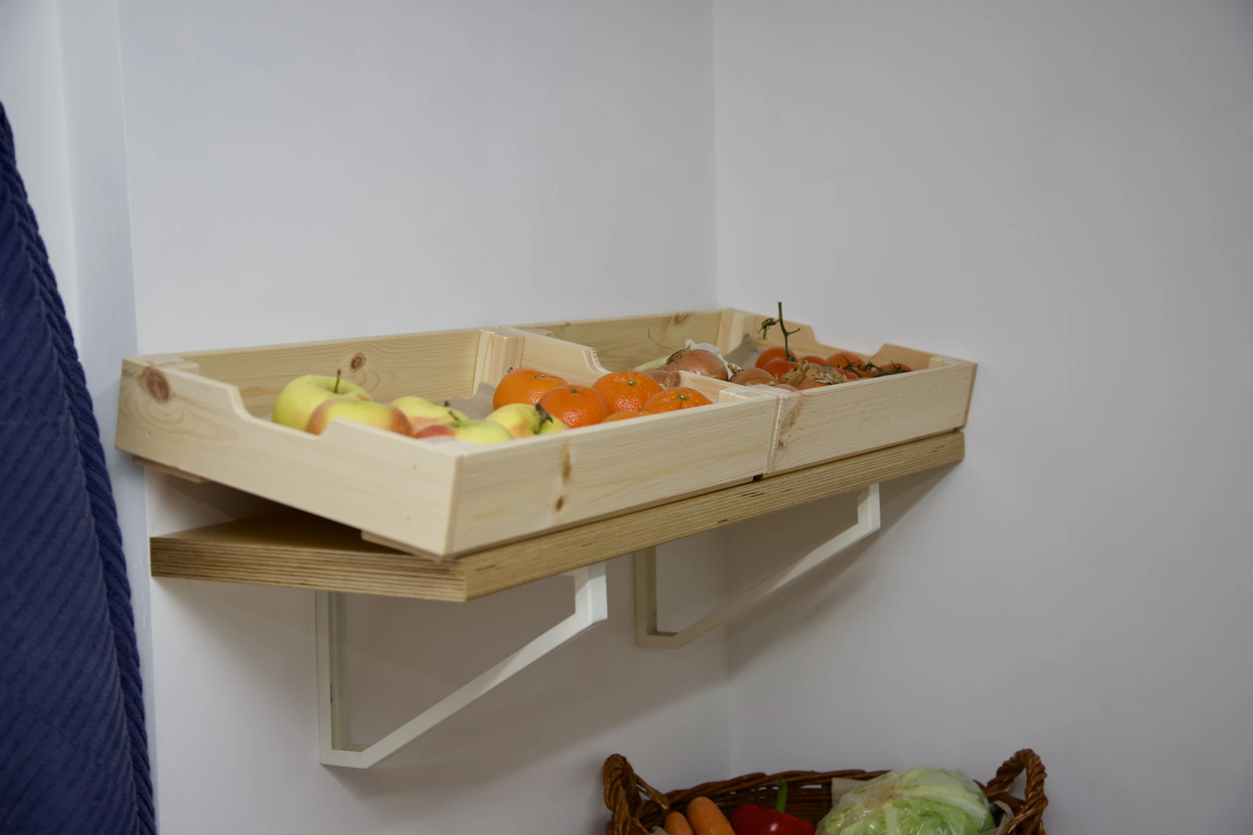 A single wooden crate of fruit mounted on a white wall