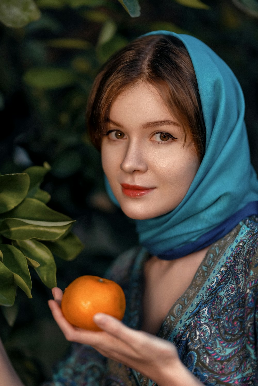 a woman in a blue scarf holding an orange