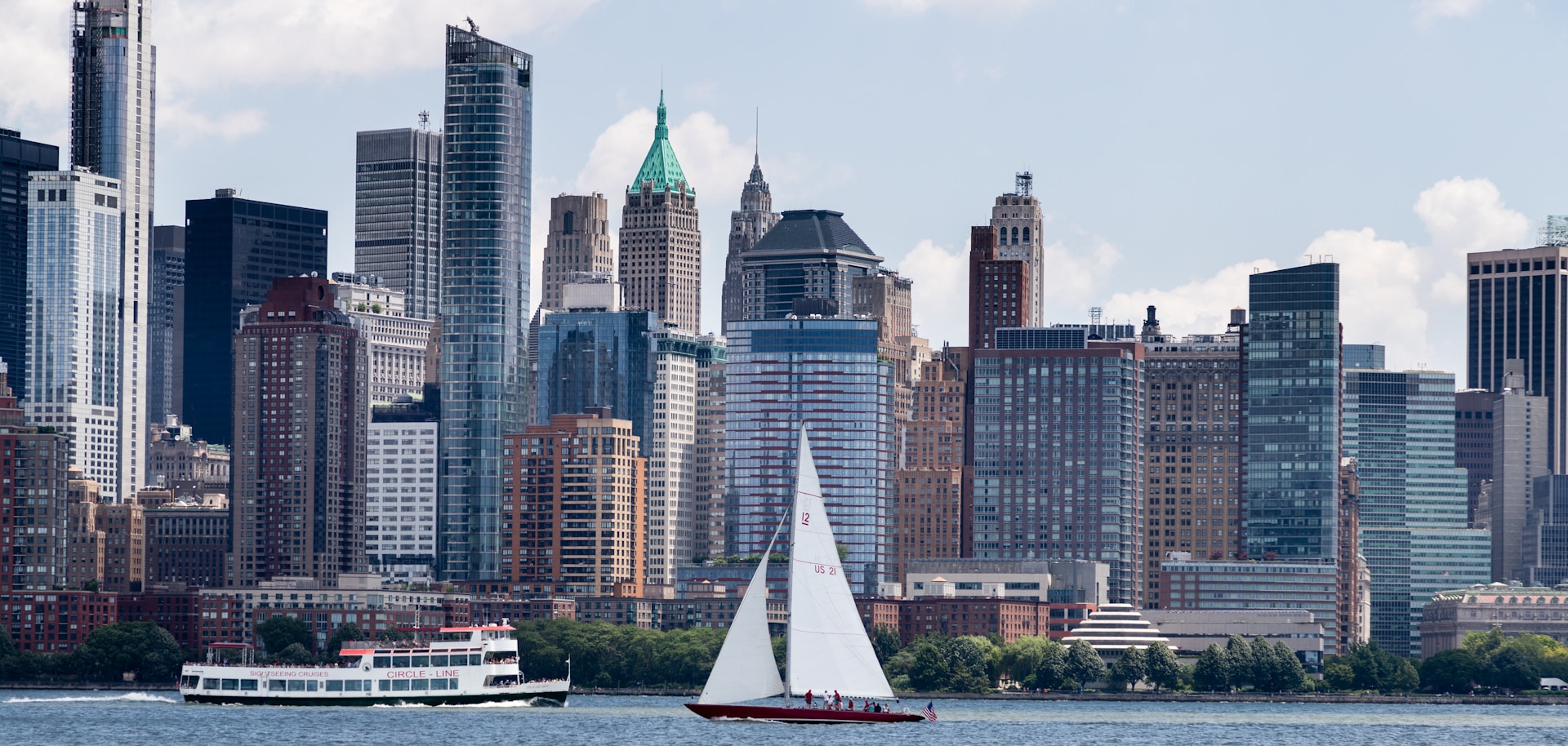 a sailboat in a body of water with a city in the background