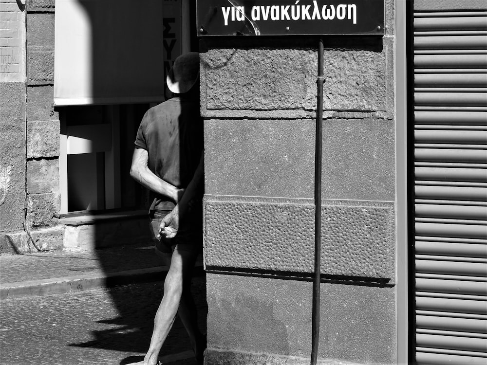 a man walking past a tall building next to a street sign