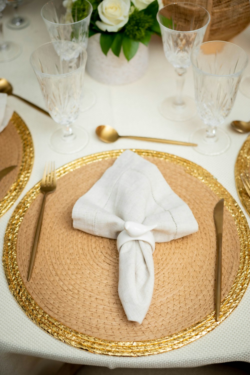 a place setting with a white napkin and gold rimmed place settings