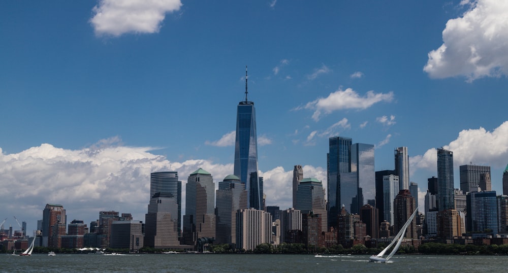 a sailboat in the water near a large city