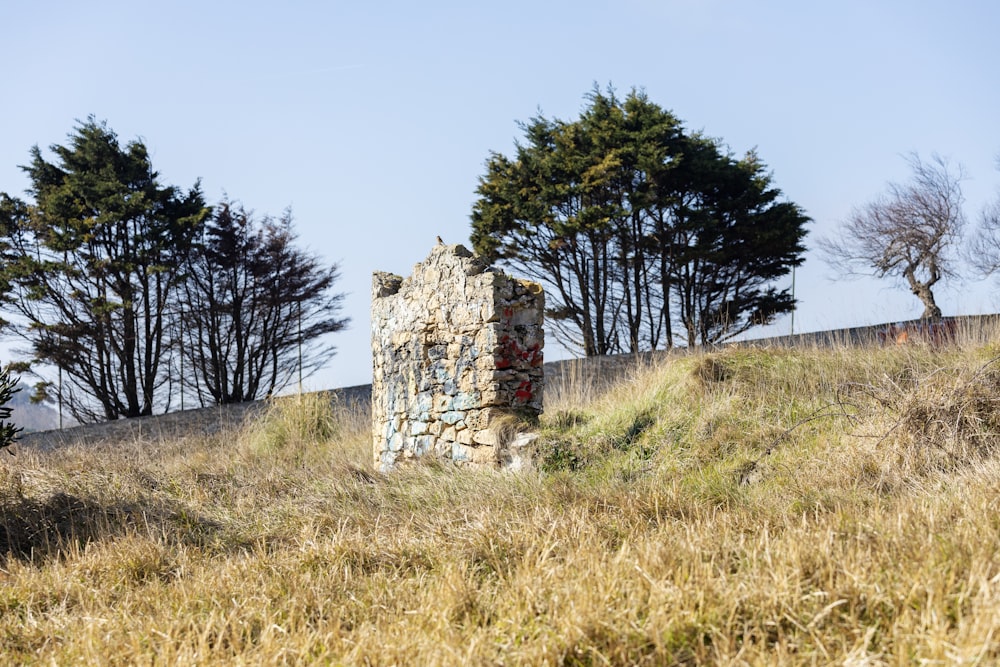 a stone structure sitting on top of a grass covered hillside