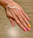 Close-up of a hand with perfectly manicured nails in soft mocha tones against a cream background.