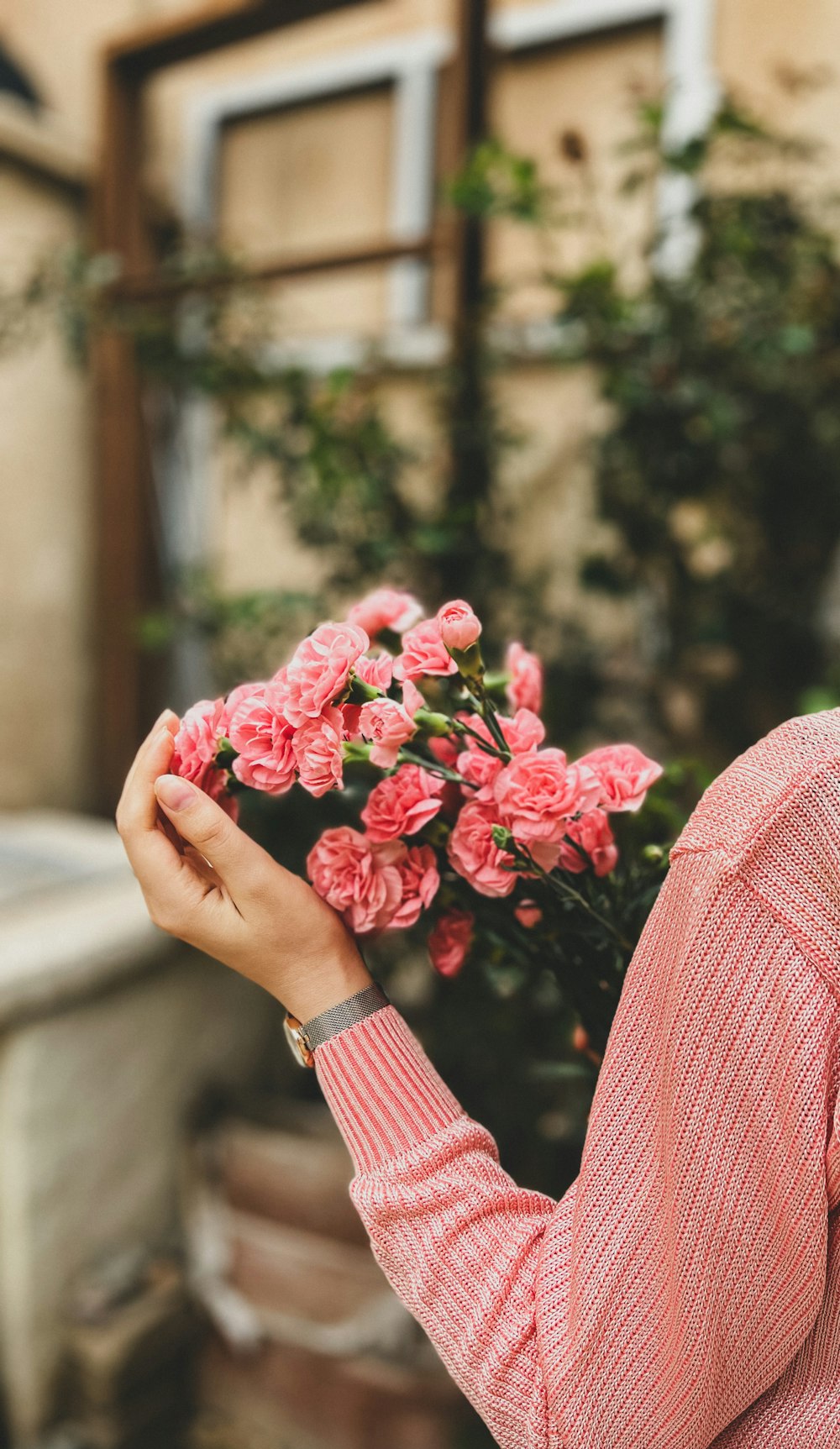 a woman holding a bunch of pink flowers