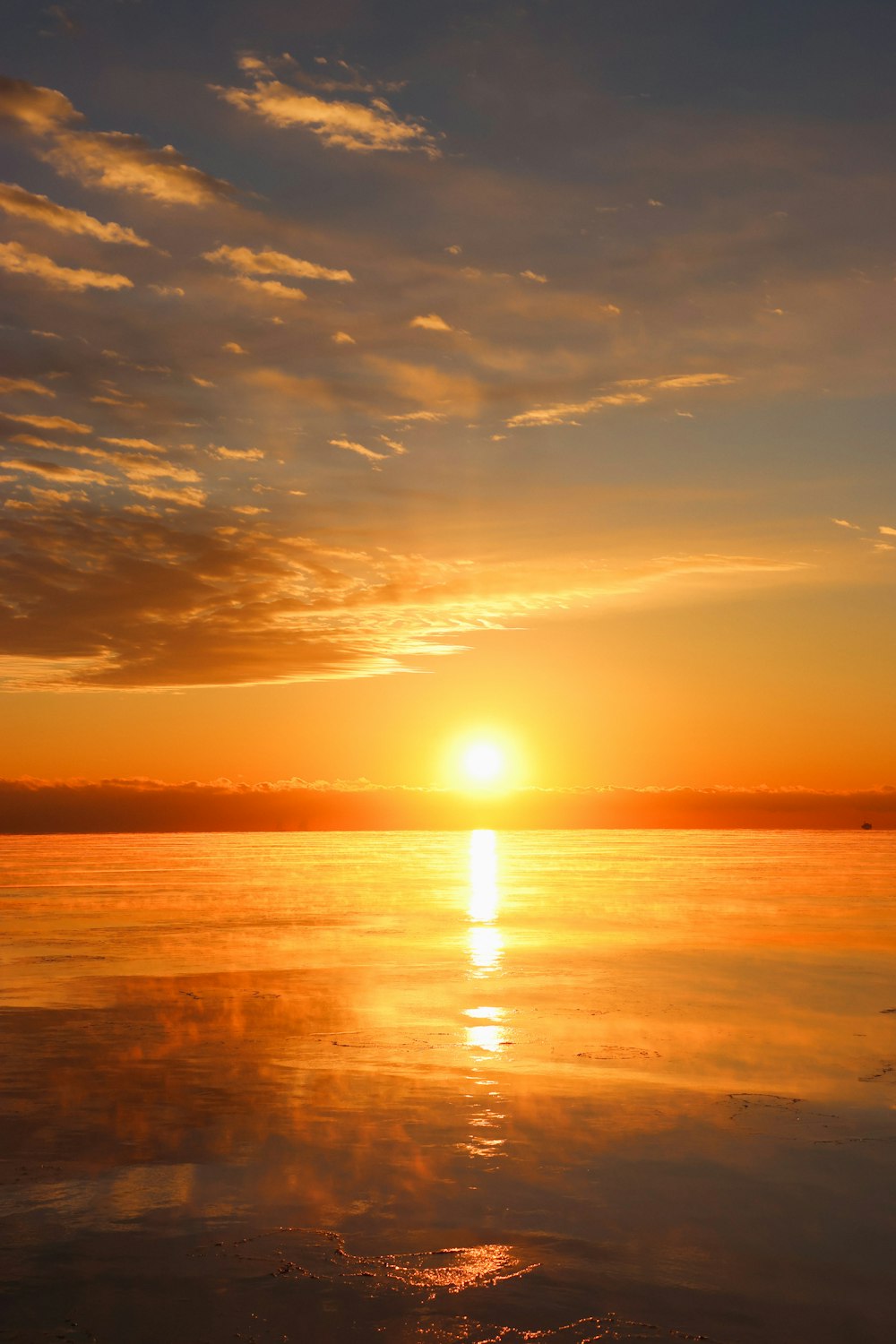 the sun is setting over the ocean with a boat in the water