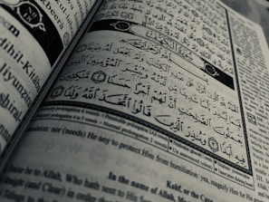 Arabic calligraphy and English text are printed on an open book page, with intricate design elements and a clear division between Arabic verse and its English translation.