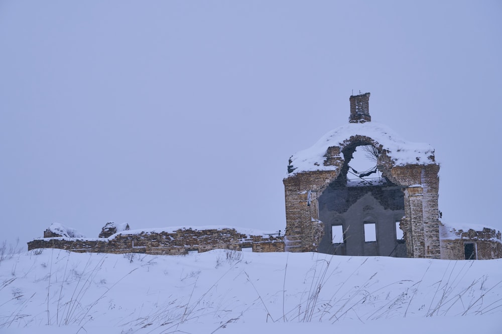 an old building with a bell on top of it in the snow