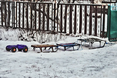 Brightly colored sleds lined up on a gentle snowy hill ready for fun.