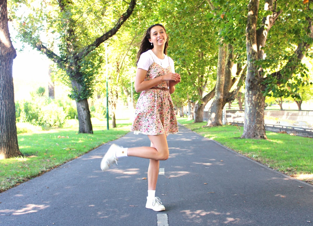 a girl is running down the road in a park