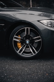 Close-up of a calm yellow car wheel in motion on dark gray pavement.