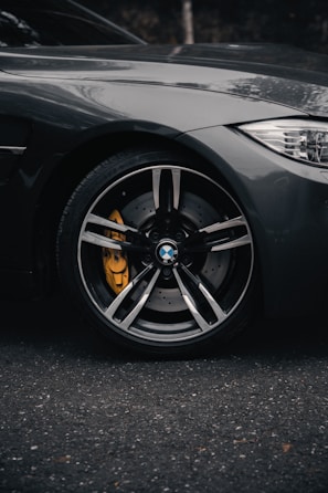 Close-up of a luxury car’s gleaming alloy wheel and tire on a smooth asphalt road