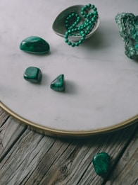 a table topped with green stones and a bowl of green beads