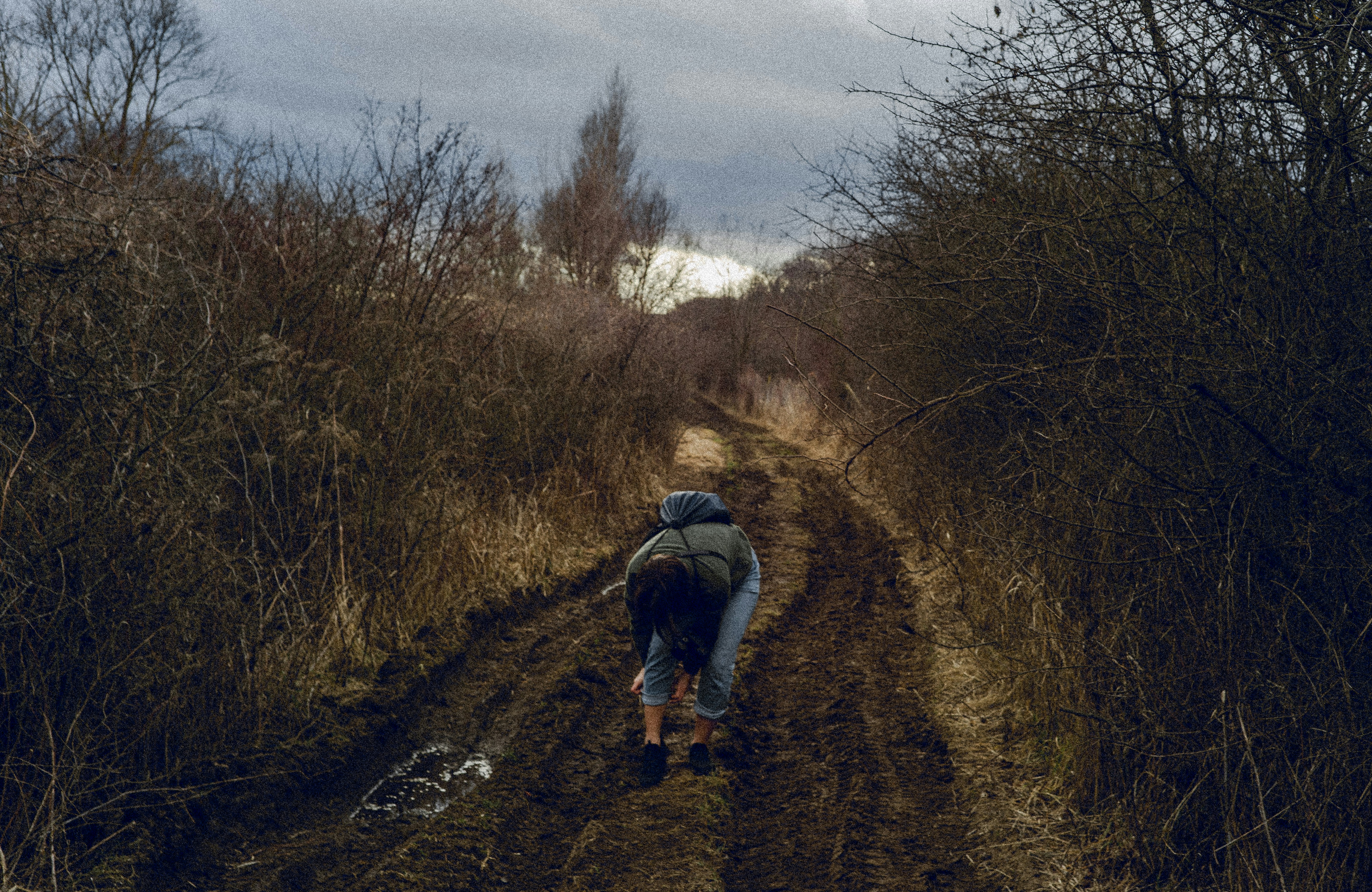 a person walking down a dirt road in the woods