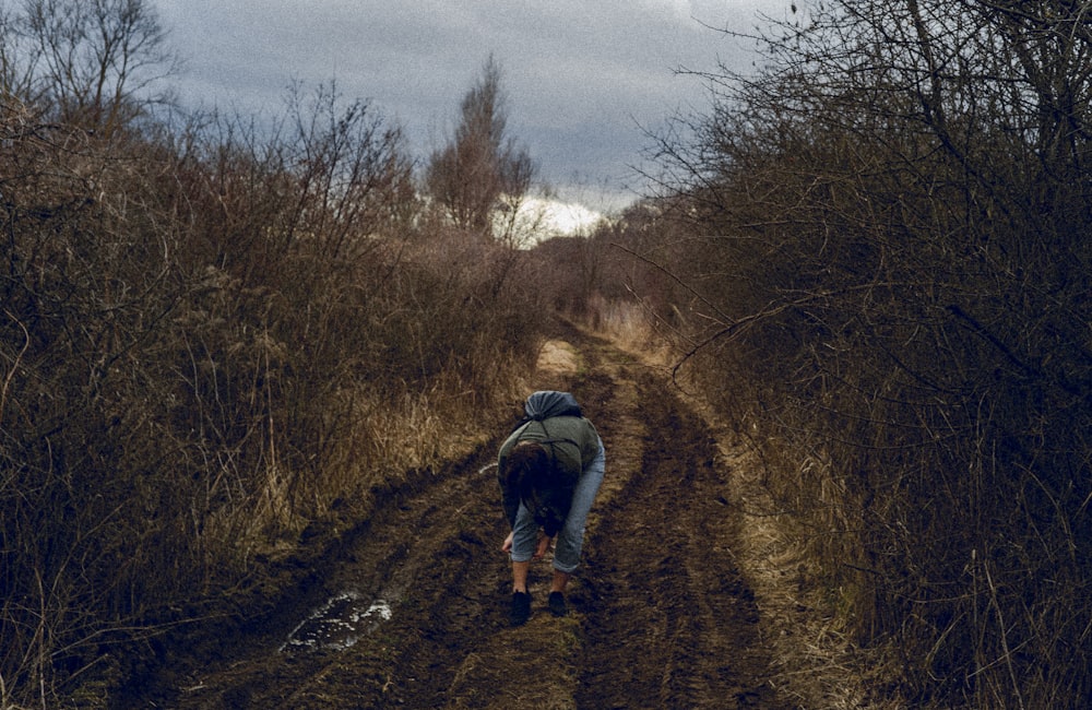 a person walking down a dirt road in the woods